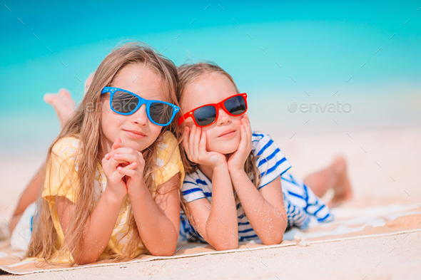 Two little happy girls have a lot of fun at tropical beach playing