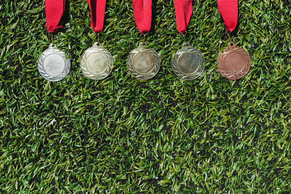 Top view of various medals lying on green grass