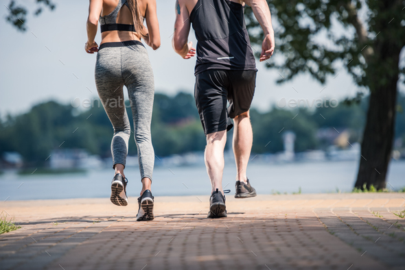 partial view of sportive couple jogging together in park