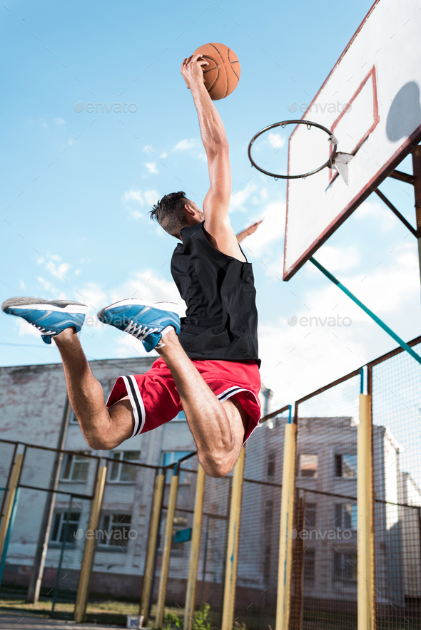 back view of basketball player throwing ball into basket during game