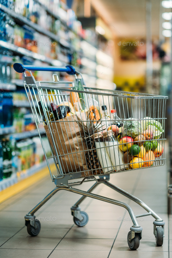 selective focus of shopping cart with purchases in supermarket