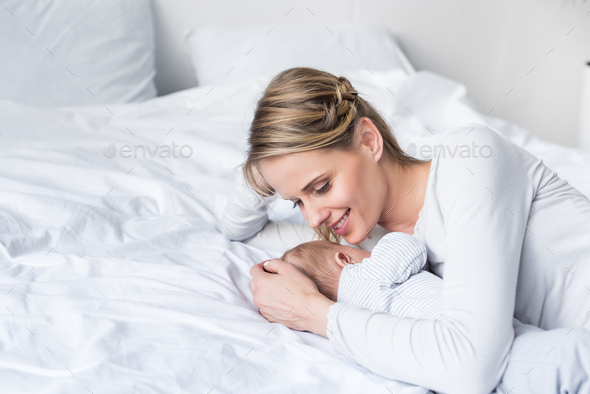 happy mother hugging her little sleeping baby in bed - Stock Photo - Images