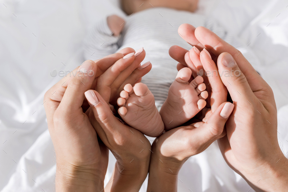 Cropped View Of Parents Holding In Their Hands Little Baby Feet Happy Family Concept Stock Photo By Lightfieldstudios