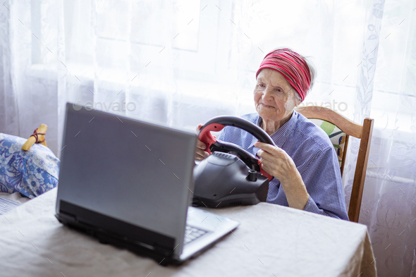 Senior woman enjoying car racing video game on laptop at home - Stock Photo - Images