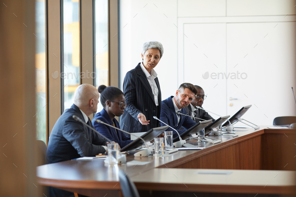 Mature businesswoman speaking during business conference at board room