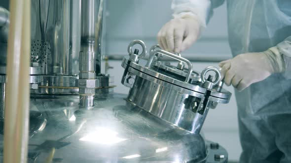Factory Worker Is Turning a Handle of a Reactor's Cistern alt
