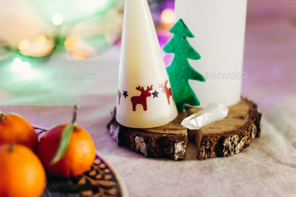 candle with reindeers and christmas tree on rustic christmas table with colorful lights - Stock Photo - Images