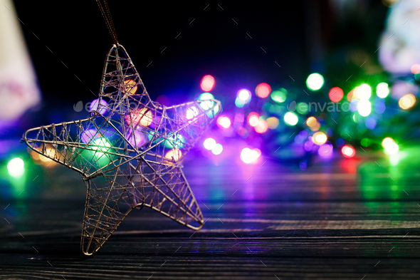 hand holding golden christmas star toy on background of colorful garland lights - Stock Photo - Images