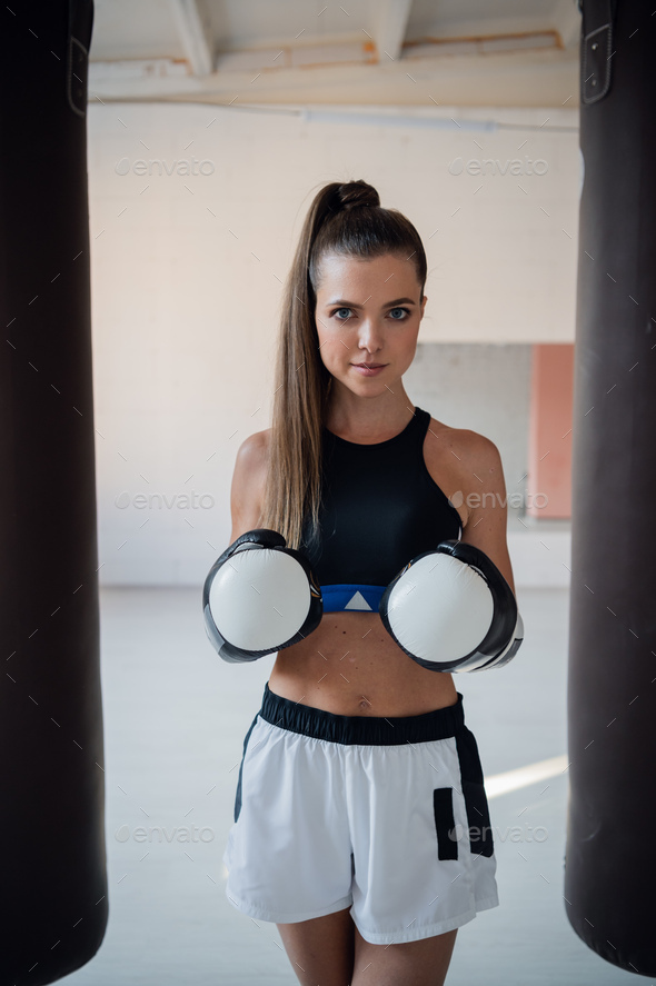 Photo shoot for a young athlete in the interior of a boxing gym with gloves and bags - Stock Photo - Images