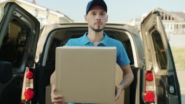 Dolly Shot of Deliveryman Carrying Parcel From Van Then Knocking on Front Door alt
