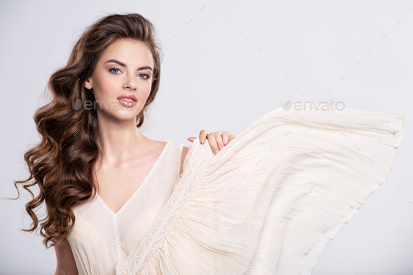 Portrait of a beautiful woman with a long hair in a beige dress.
