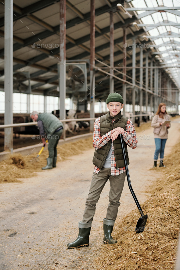 Content teenage boy working with parents at farm