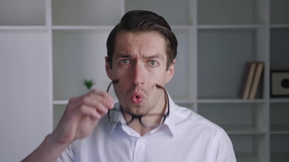 Shocked Male Businessman in White Shirt Takes Off Glasses and Say What alt