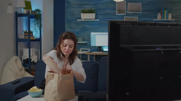 Young Woman Putting Bag of Takeaway Food on Table alt