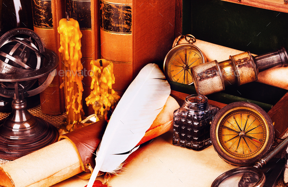 Old books, feather pen and ink bottle, old scroll with red wax seal, vintage compass. Adventure stories background.