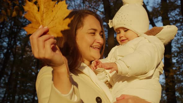 Mom plays with her daughter in the autumn park