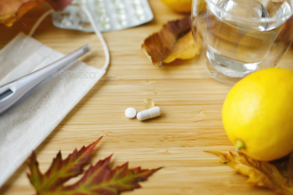 Vitamin D, vitamin C and zinc pills on table with face mask, lemons and fall leaves. Boost immune