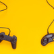 Two wired gamepads or video game controllers on yellow background - PhotoDune Item for Sale