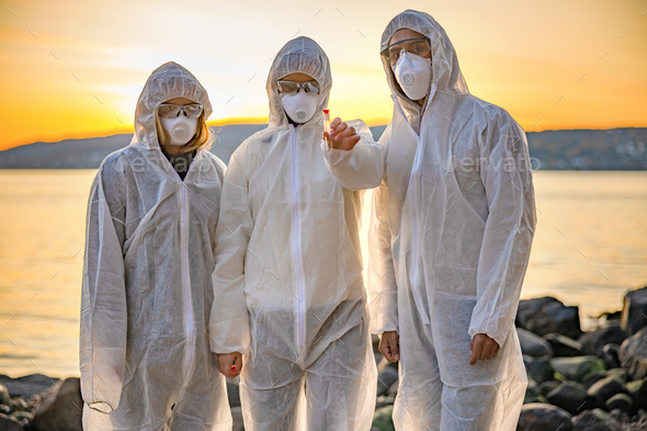 Dedicated team of scientists holding water sample at beach - Stock Photo - Images