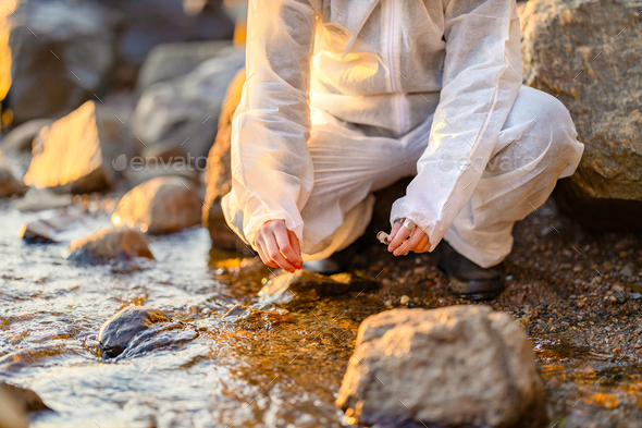 Close-up of researcher collecting water sample at seashore - Stock Photo - Images