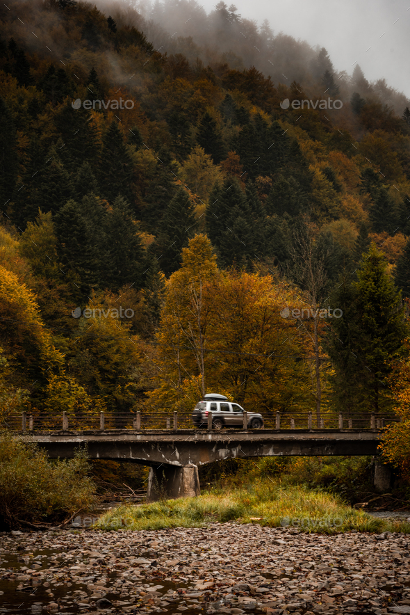 Adventure Road Trip. Car Drives Over Old Bridge in Mountains. Active Outdoor in Wilderness.