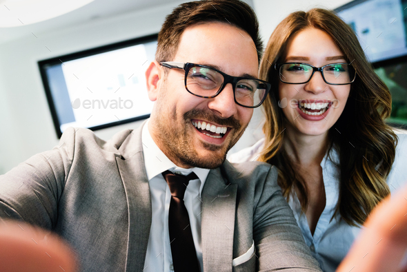 Young happy colleagues having fun while taking selfie in office Stock Photo  by nd3000
