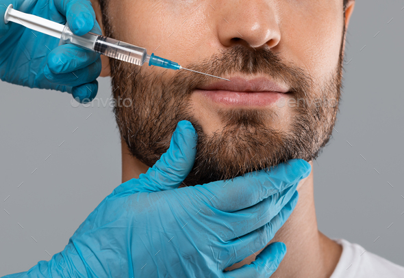 Unrecognizable bearded man getting lips filler in beauty salon