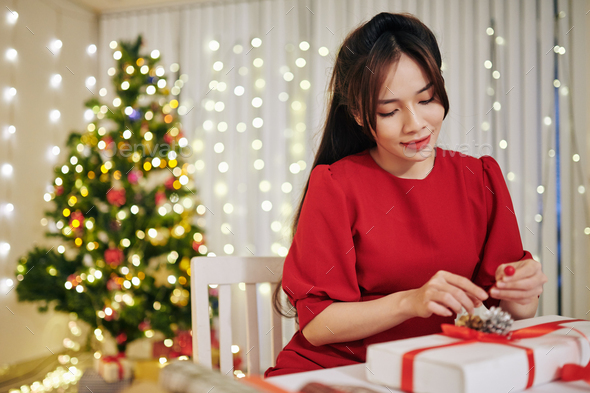 Lovely Charming young Vietnamese woman packing Christmas presents for friends