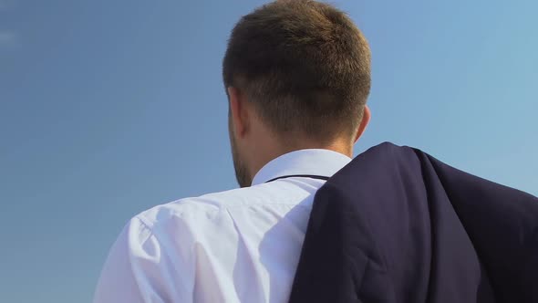 Inspired Male Boss Putting Jacket on Shoulder and Enjoying Skyscape, Back View