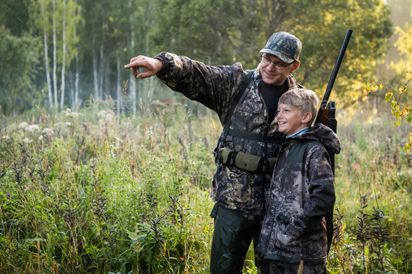 A young boy on the hunt with an experienced instructor in the forest. Autumn. Hunting for upland wildfowl