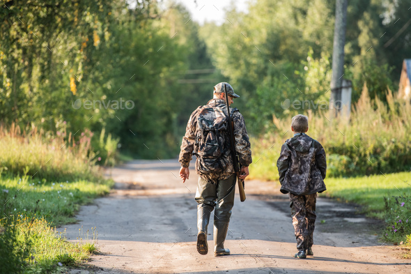 A young boy on the hunt with an experienced instructor in the forest. Autumn. Hunting for upland wildfowl