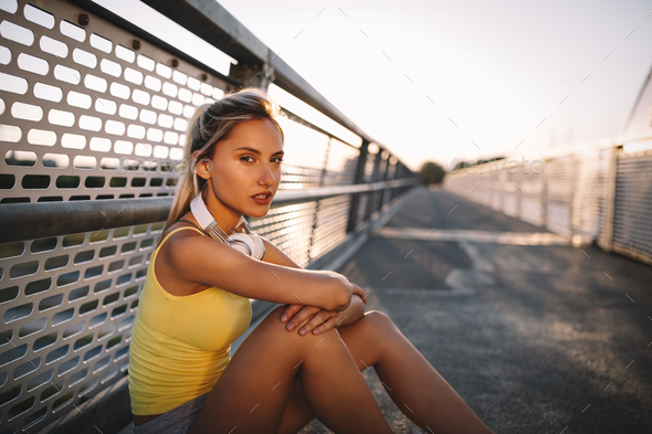 Portrait of fit cheerful blonde woman resting after a run in a city - Stock Photo - Images
