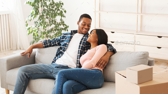 Happy black couple hugging on comfy couch in their new house after ...