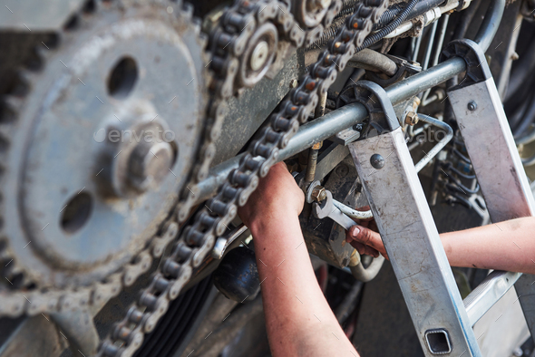 Combine machine service, mechanic repairing motor outdoors