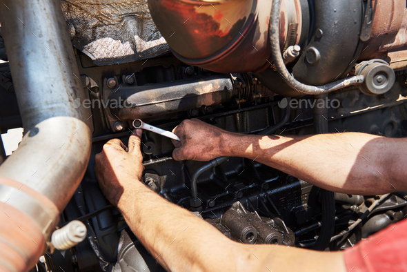 Combine machine service, mechanic repairing motor outdoors
