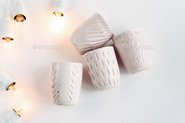 stylish creative ceramics cups and christmas garland lights, holiday celebration concept