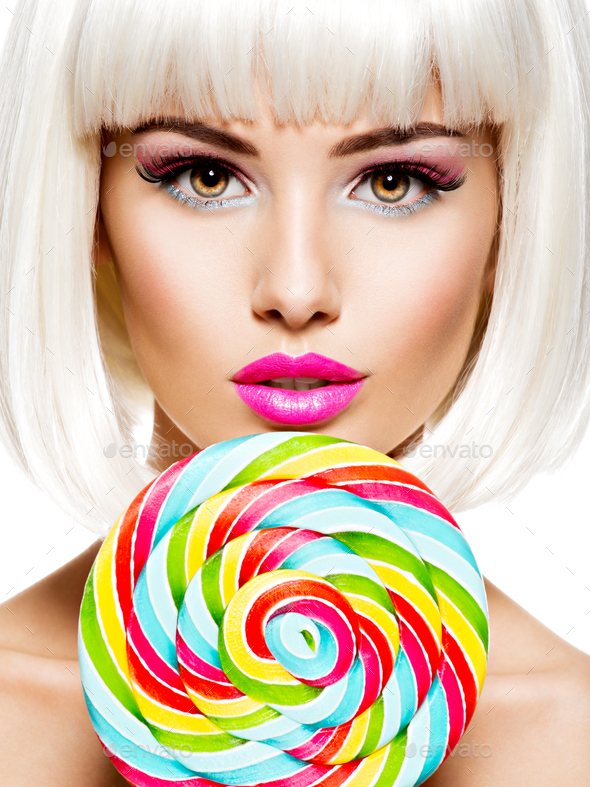 Face of a beautiful girl with pink make-up and multicolor sweet candy. - Stock Photo - Images