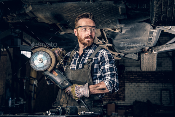 Mechanic in protective googles holds angle grinder. - Stock Photo - Images
