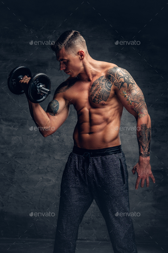 Athletic male with tattoo on his chest doing biceps workouts wi Stock Photo  by fxquadro