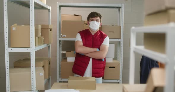 Man Wearing Red Vest Protective Gloves and Mask Employee of Warehouse Standing on the Background of alt