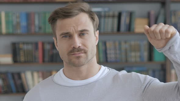 Thumbs Down by Adult Man at Work,  Looking at Camera alt