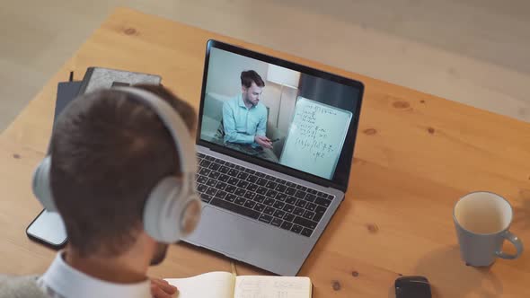 Man Student Sits at a Desk at Home and Study Online Using a Laptop Student Learns in a Remote Lesson alt