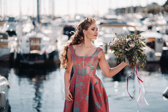 Young model girl in a beautiful dress with a bouquet of flowers on the ...