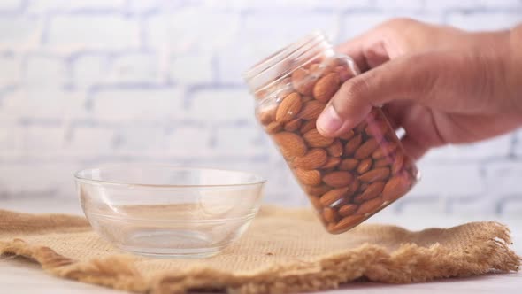 Pouring Almond Nuts in a Bowl on Table alt