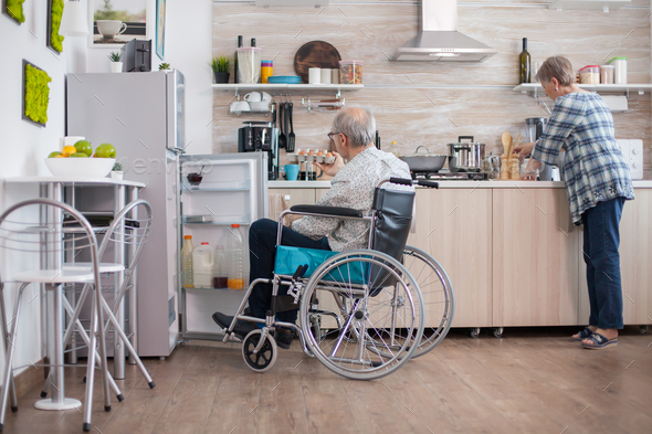 Handicapped man helping wife at the kitchen