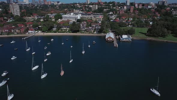 Sydney Harbor on a beautiful sunny day from Double Bay featuring boats, blue sky and water. Drone sh alt