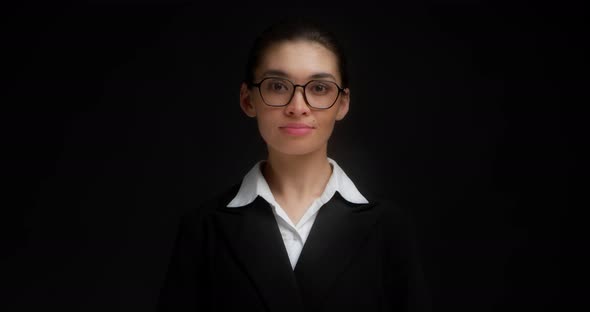Asian Business Woman in Glasses and Formal Clothes Stands and Looks at Camera