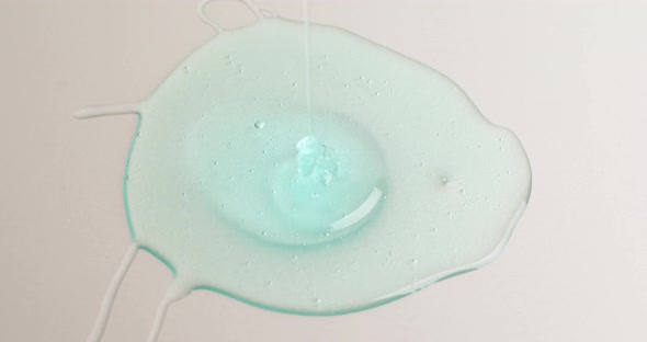 Blue cream liquid gel serum pours on grey texture, makeup