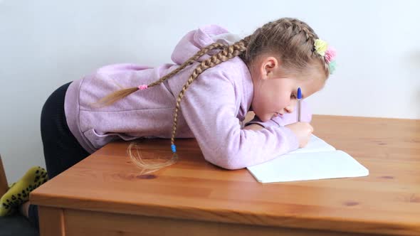 Little Girl Makes the Lessons at Home at the Table alt