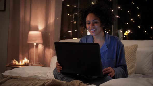 Woman with Laptop Has Video Call in Bed at Night
